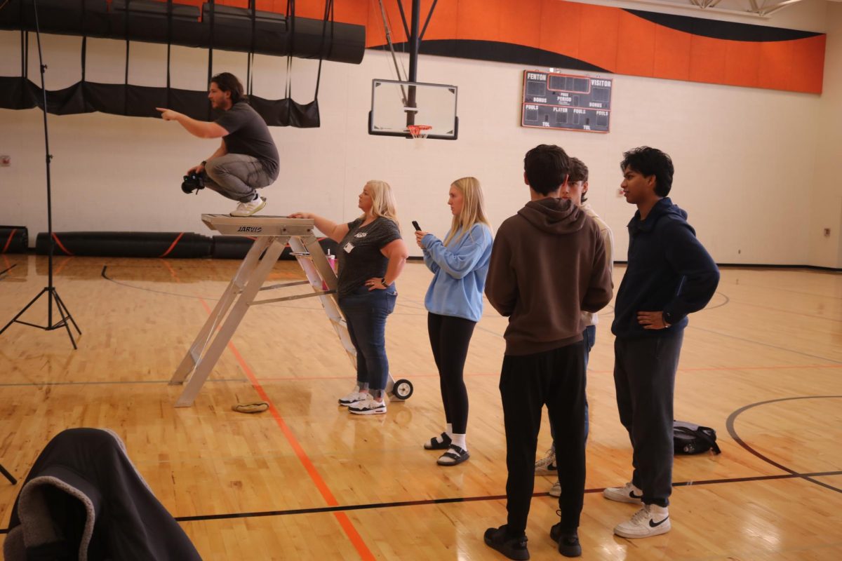 Taking a placeholder, senior Shea Temrowski helpss during club photos. On, Nov. 9, The Fentonian staff worked club photos in the Auxiliary Gym during SRT.
