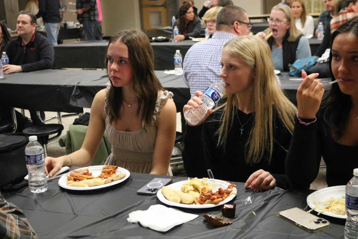 Eating, freshmen Caelyn Bono and junior Izzy MacCaughan attend a cross country banquet. On Nov. 8, the cross country team held a banquet to celebrate their season. 