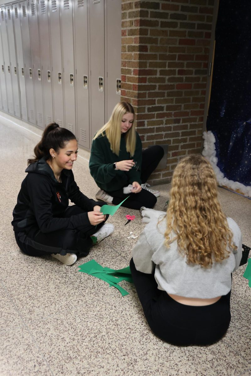 Cutting the paper, junior Ava Slezinski decorates her SRTs door for the door decorating contest on Dec. 6. The winner of the contest will be announced on Dec. 14.