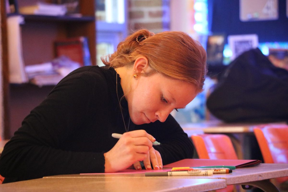 Decorating, Senior Nina Frost makes Christmas cards for children. On Dec. 11, Student Council and NHS gathered in Mrs Hazletts room to make Christmas cards.