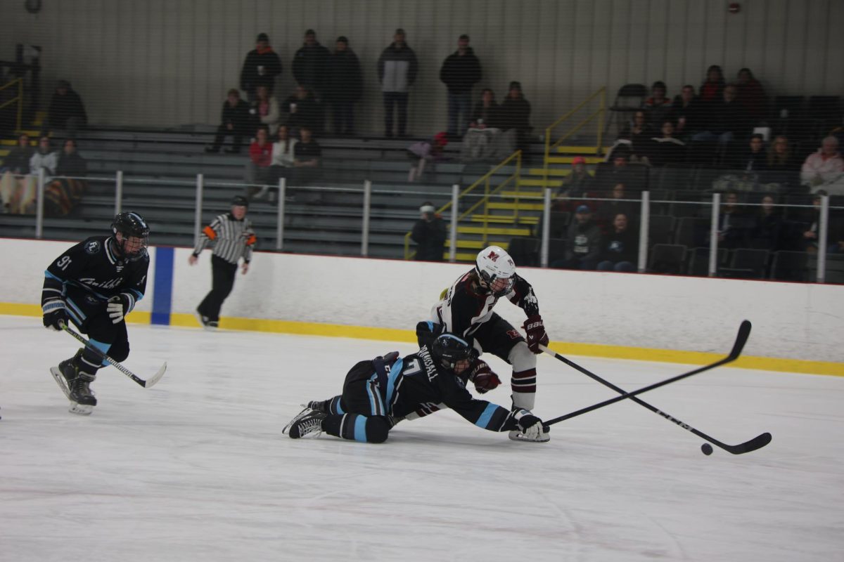 Sliding to win the puck, junior Brennan Crandall plays strong defense against Milford. On Dec. 3, the Griffins lost 6-2. 