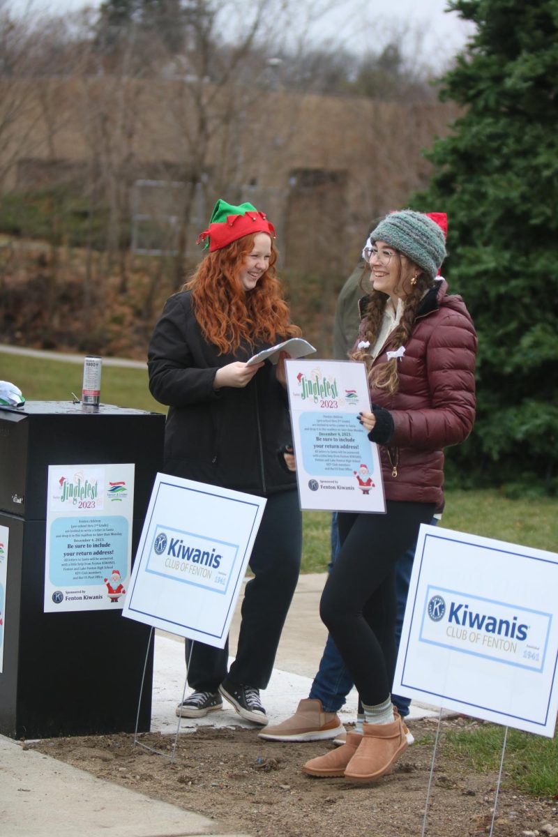 Laughing, juniors Ariana Papcun and Ella Eversole help with jingle fest. On Dec. 2, the key club gathered in front of the community center to help hand out gingerbread houses.