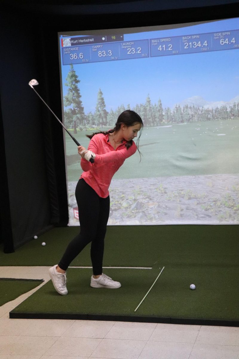 Swinging, Sophomore Isabel Bhagat is about to hit the golf ball. On Jan. 4, the Fenton golf simulator opened. 