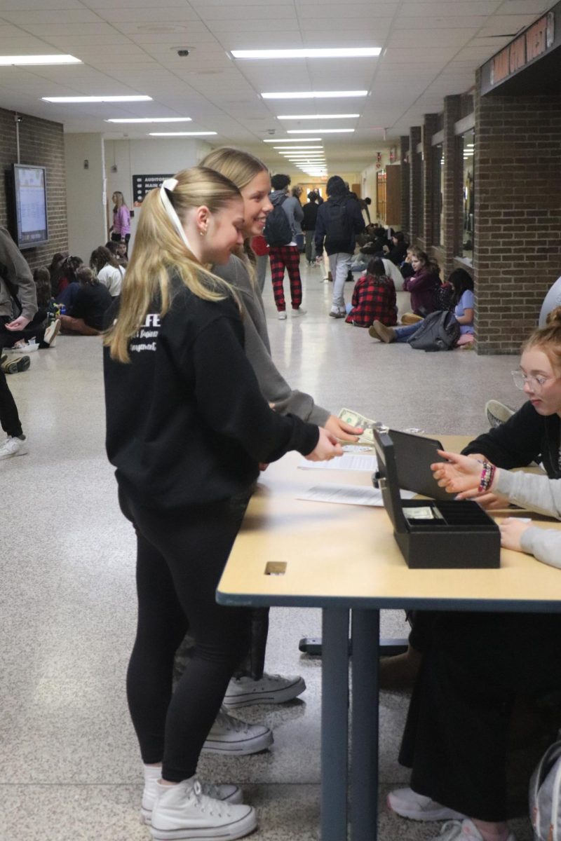 Handing in money, Sophomores Evie Metcalfe and Kallyn Sprague are buying tickets. On Jan. 25, Student Council was preparing to sell tickets for the winter dance.