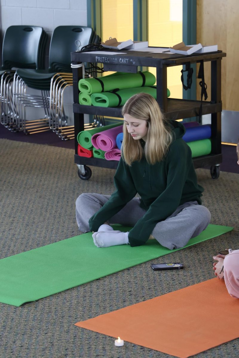 Stretching, junior Iris Bravender participated in yoga with Sunny. On Jan. 30, Bravender and a group of girls joined the librarian in the project room during srt. 