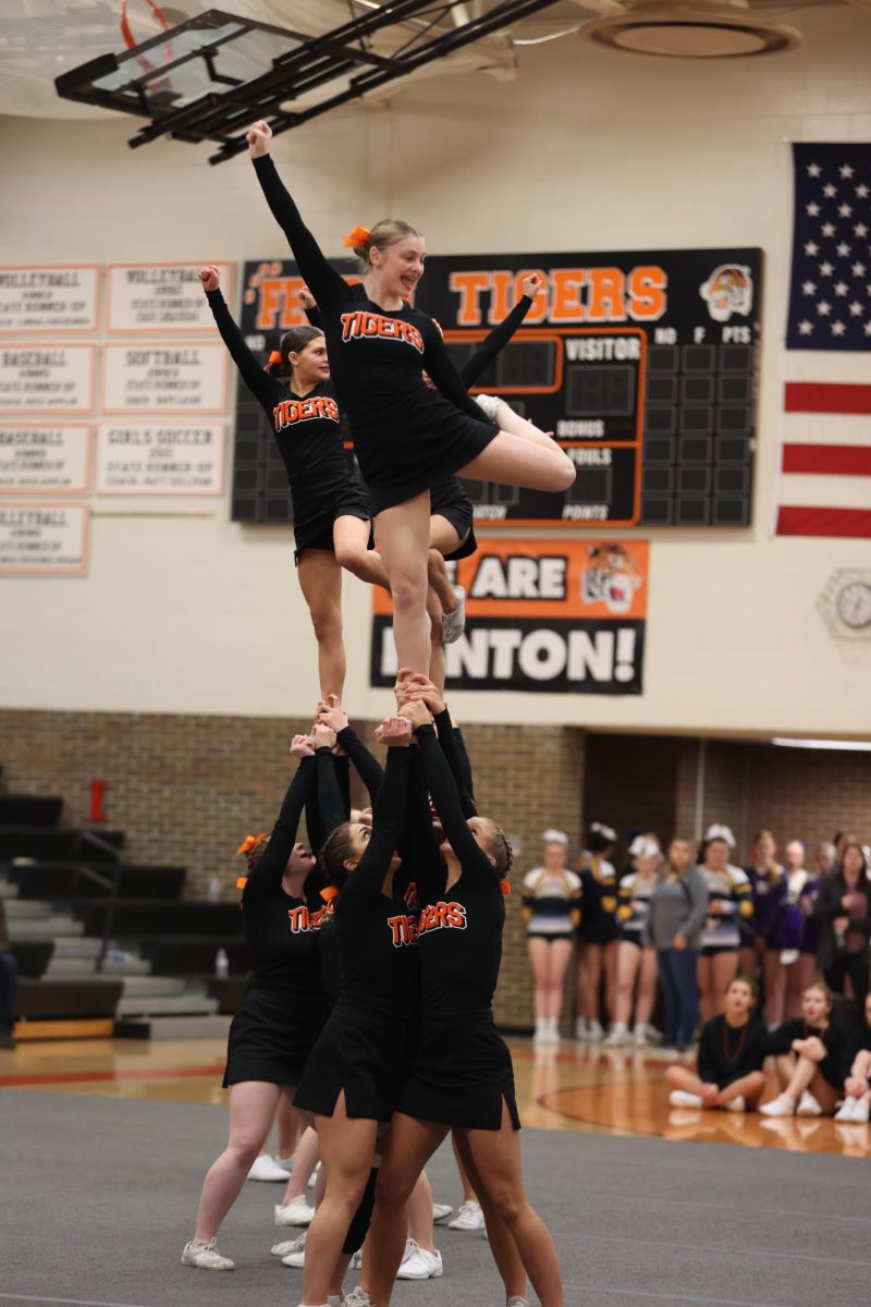 Smiling to the audience, sophomore Evie Metcalfe shows off her skill. On Feb. 3, the Fenton Cheer team placed second.  