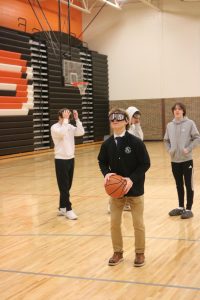 Using the drunk goggles, senior Henry Wojtaszek attempts a free throw shot. On Feb. 2, teacher Matt Sullivan brings his class to the gym to do drunk tests with some officers.