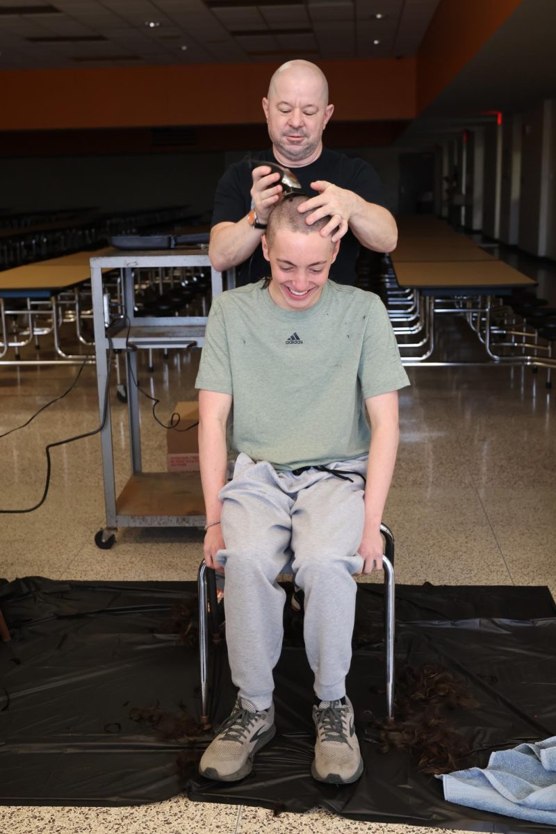Losing his hair, sophomore Nate Hartzell lets Head Coach Brad Jones shave his head. On Feb. 21, the boys swim team carries their tradition of shaving their heads the day before Metro Prelims.