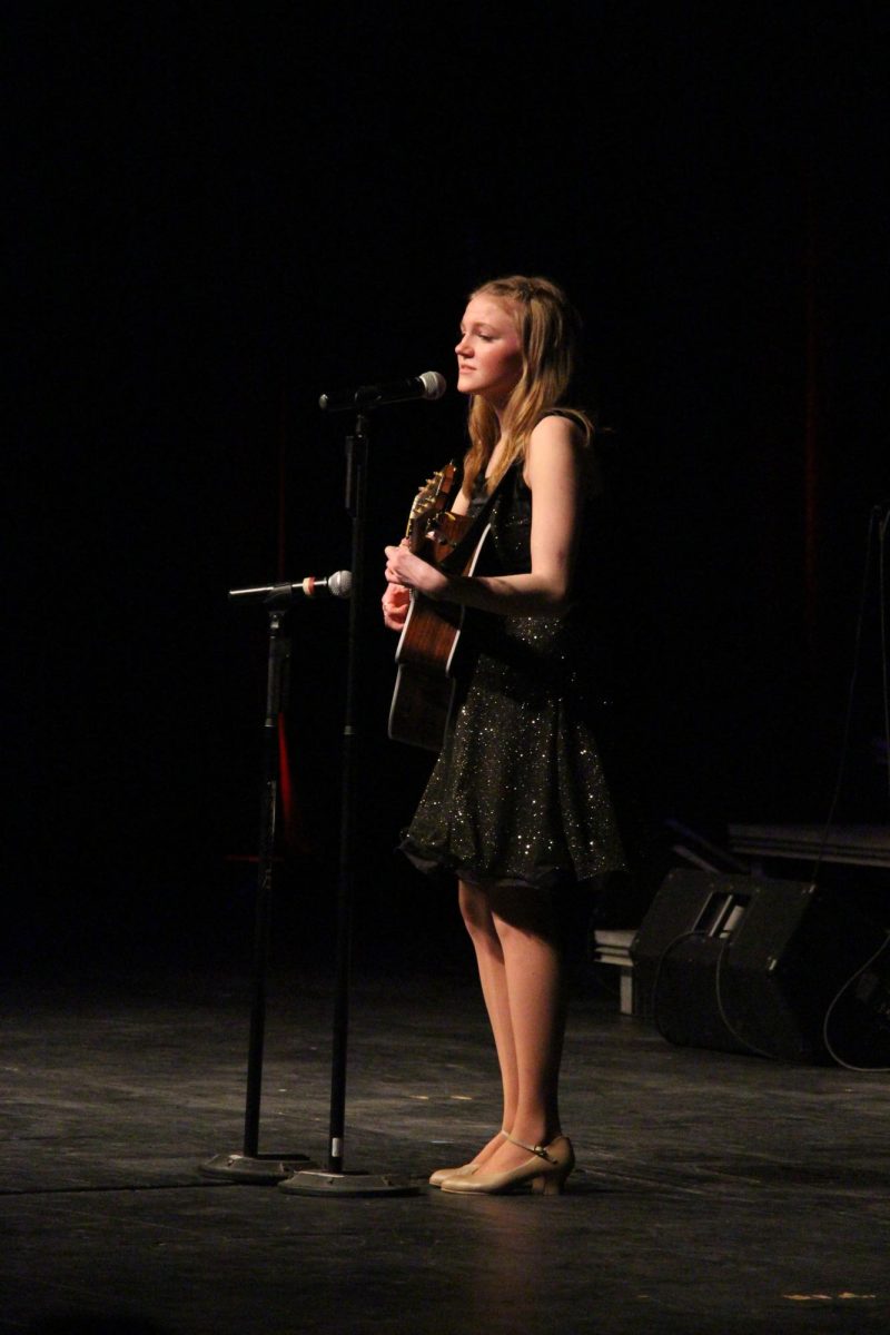Playing her guitar, senior Julia Blanchard sings her solo. On Feb. 23, the Ambassadors concert took place in the Auditorium. 