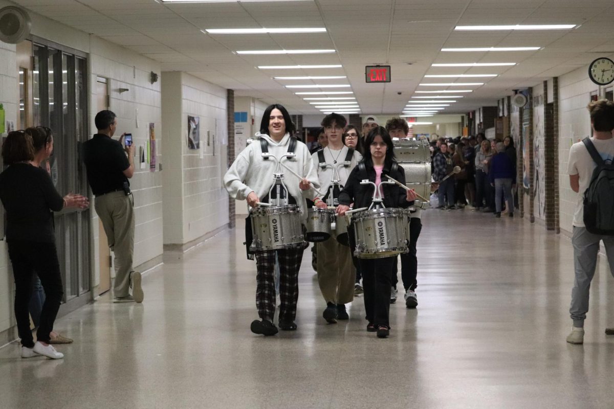 Leading the band, junior Jonah Andrews plays while walking through the hallway. On Feb. 23, students lined the halls to support the ski team as they leave for states.