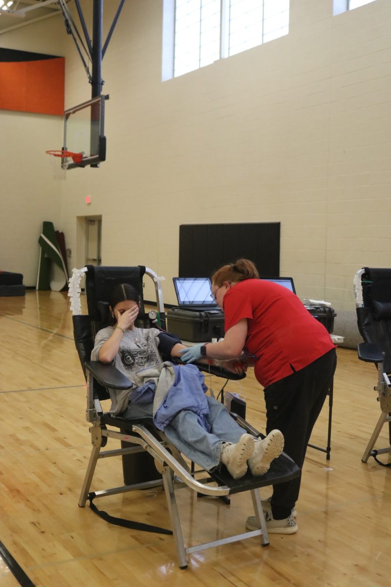 Looking away, junior Paige Harrison gives blood to save a life. On Feb. 2, National Honor Society hosts the second blood drive of the year.
