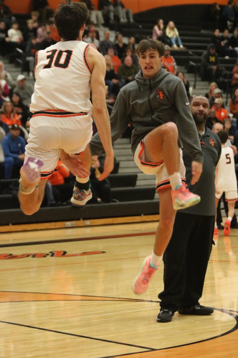 Jumping in the air, senior Nicholas Simeoni goes in for a jumping high five with his teammate. On Feb. 2 the boys varsity takes on the Swartz Creek dragons and won 71-55.