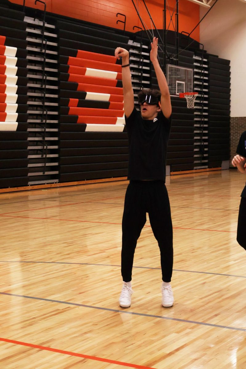 Shooting a free throw, junior Gavin Yanez tests out his shooting skills with drunk goggles. On Feb. 2, science teacher Matt Sullivan let his students try on drunk goggles so they could see what it would be like to be drunk.