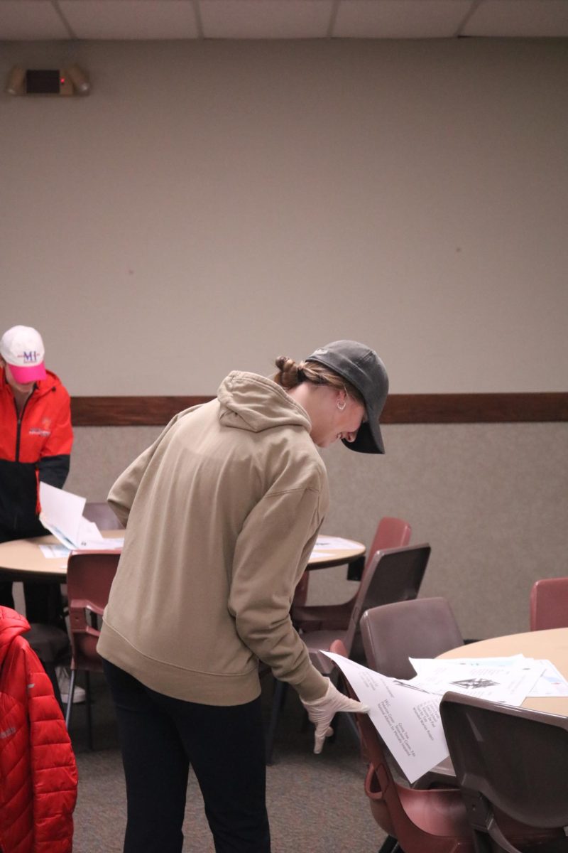 Putting down papers, junior Abby Dekraker sets up a table. On Feb. 23, Students in National Honors Society helped out with a fish fry.