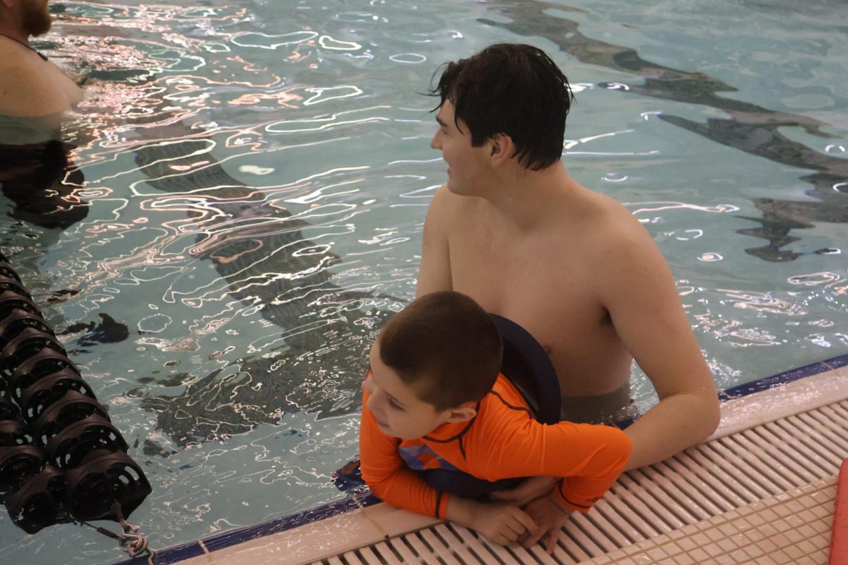 Helping, Senior Christopher Curtis helps a kid out of the pool. On March 5, FHS peer to peer participants sawm with World of Wonder students. 