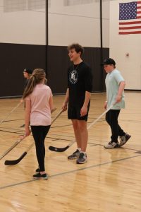 Volunteering at the hockey lock-in, senior Max Wright teaches the younger kids how to play hockey. On Mar. 15, the Fenton-Linden Griffins held a fundraiser at Fenton High School.