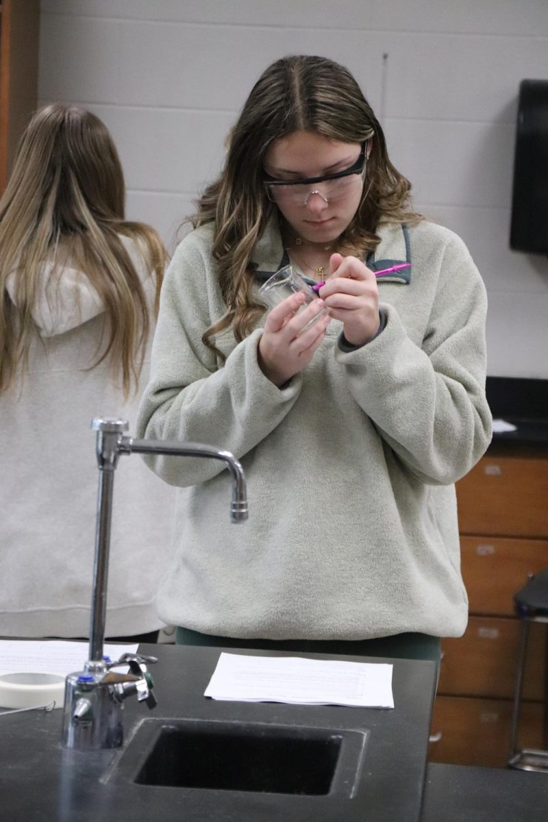 Holding a pencil, Sophomore Grace Perry labels a beaker. On Mar. 19, Mr. Millers class completed a nail lab. 