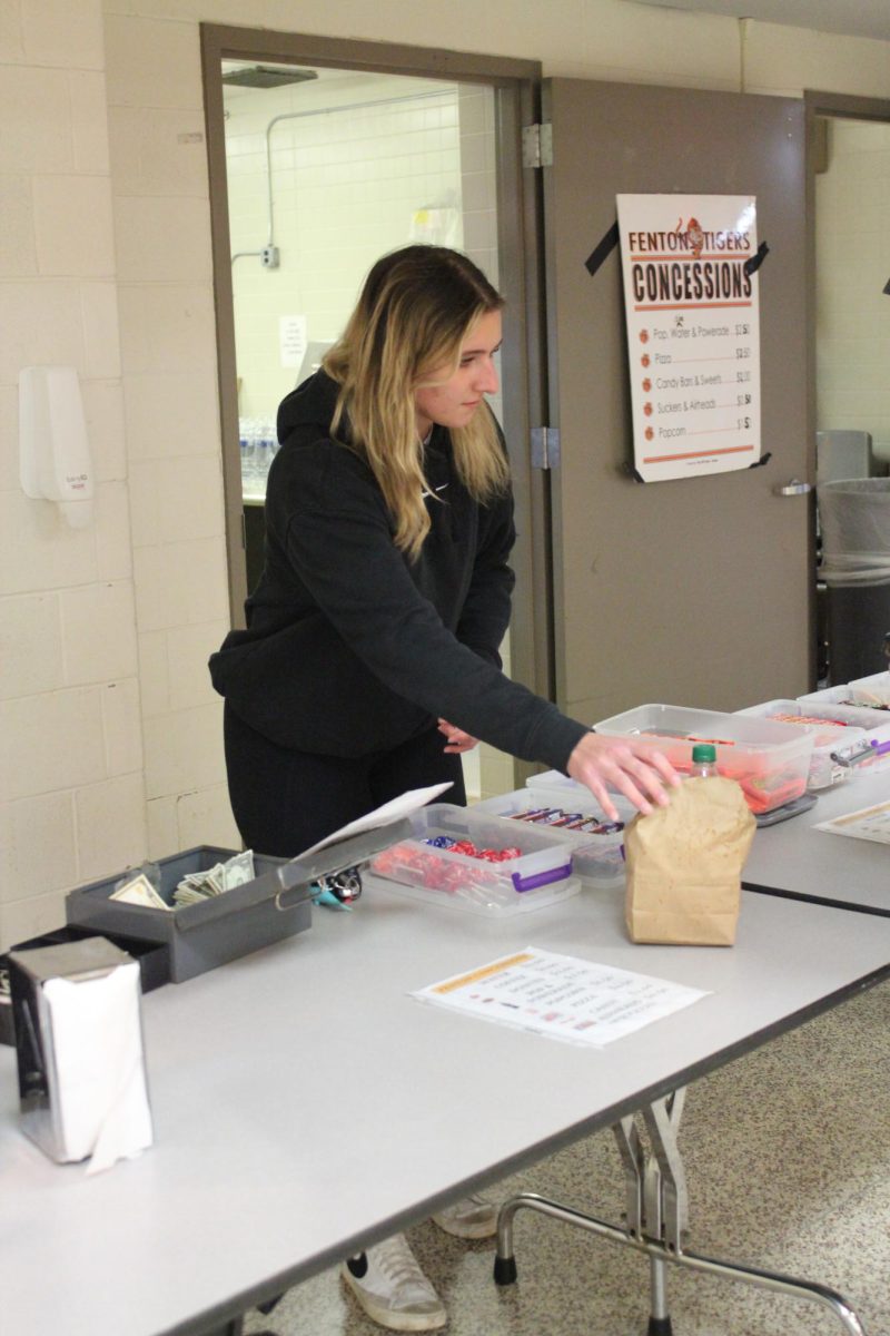 Working the concession, Senior Jena Fijolek is handing out bags of popcorn. On March. 8, Key Club was working for the girls basketball game concessions. 