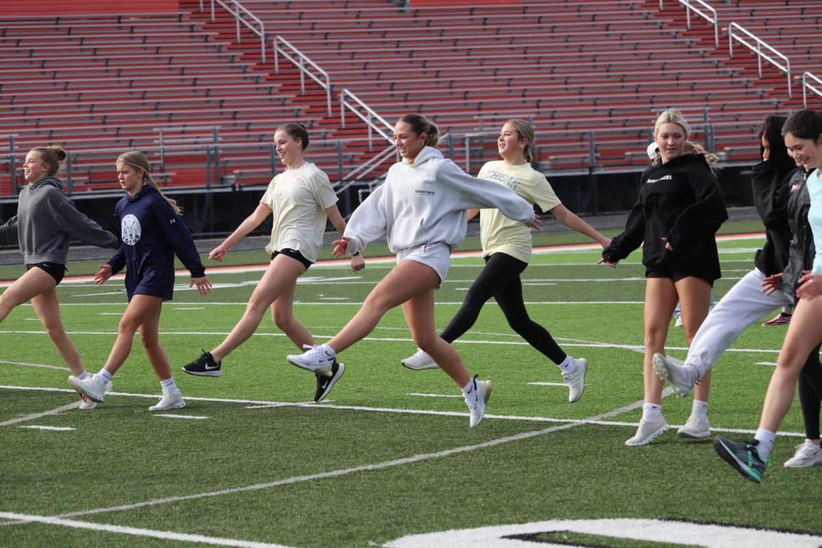 Running with straight legs, sophomore Audrina Becker participated in warmups. On March 7, he girls lacrosse team held speed and agility training on the football felid for the pre season.