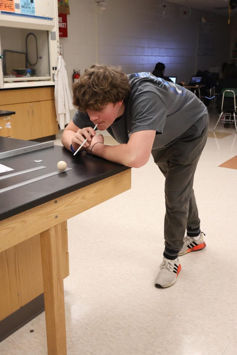 Blowing spheres, sophomore Stark Conly participates in a lab in Mr. Kasaks class. On March 5, the sophomore class in physical science completed an inertia lab.