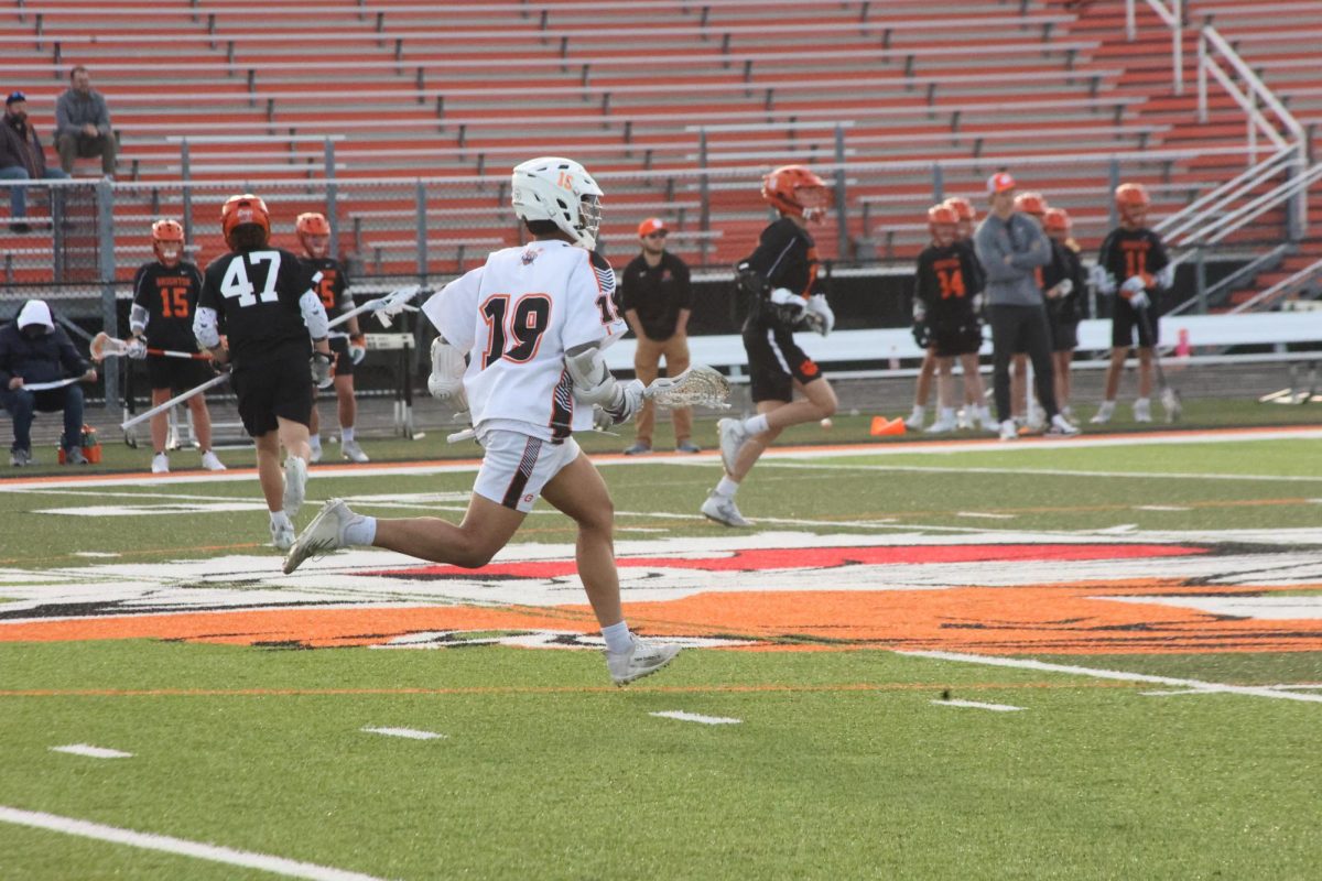 Running down the field, senior Tahseen Rahman  aims to defend his goalie. On Apr. 22, the JV lacrosse team had a game against Brighton and lost 1-14.