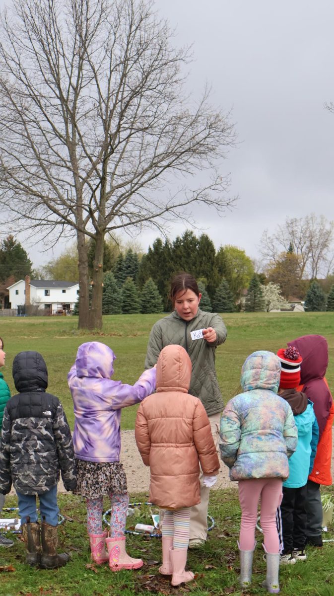Talking to the first graders, senior Katelynne Scott volunteers at the pond day field trip. On April 24, FHS Eco Club held a pond day field trip for the elementary schools. 