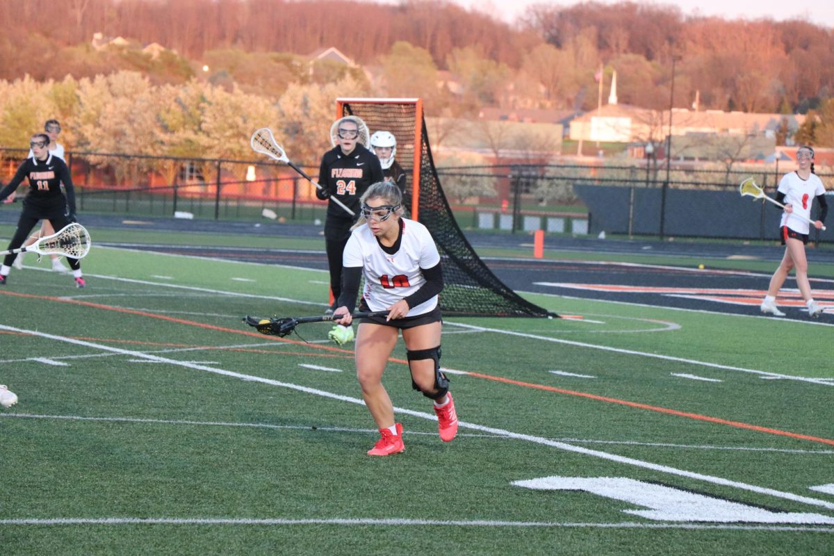 Watching the ball, Senior Chloe Justus makes a catch. On Apr. 19, the varsity lacrosse team played Flushing and won with a score of 9-8 and went into double overtime. 