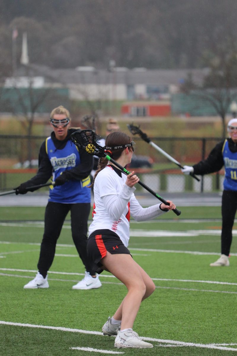 Going for a shot, junior Paige Harrison plays along with the rest of her team against Lake Fenton/Goodrich. On Apr. 12, the Heat Lacrosse team won 7-4. 
