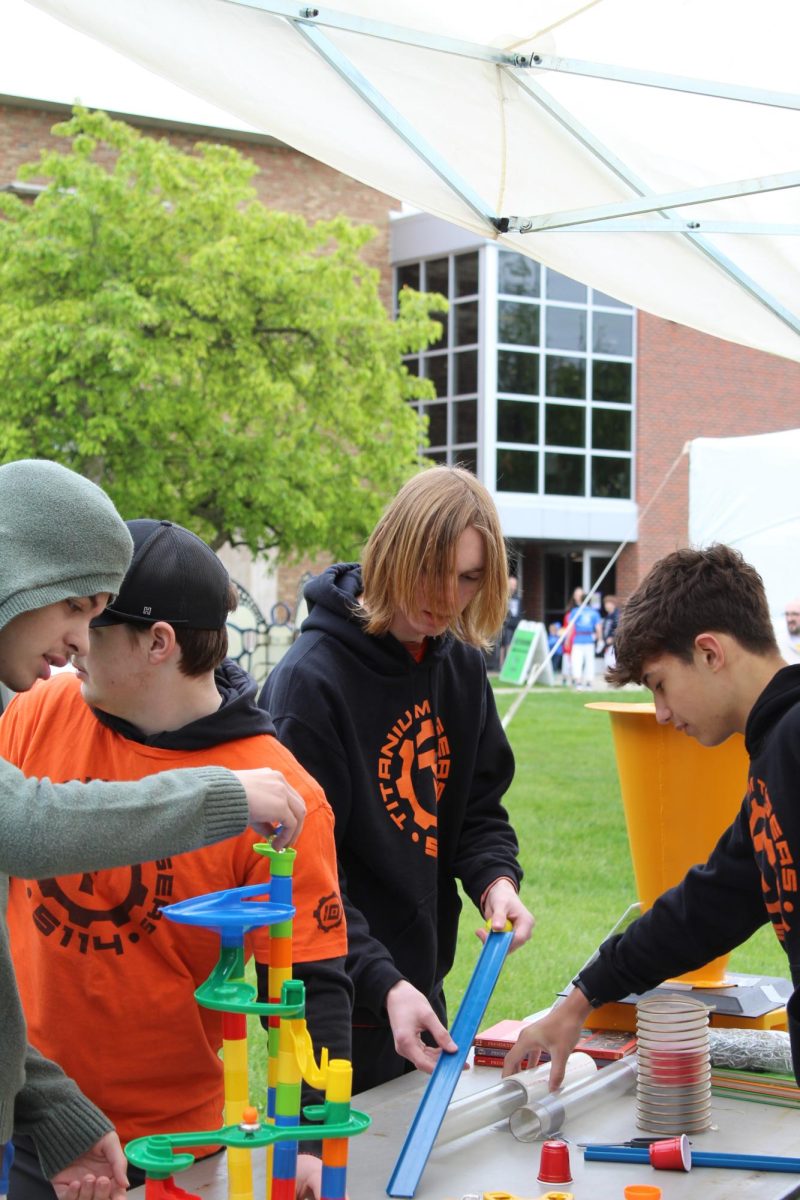 Adding a slide, sophomore Caleb Wolner fixes the marble run. On May 11, the Fenton Robotics Team had an open house.