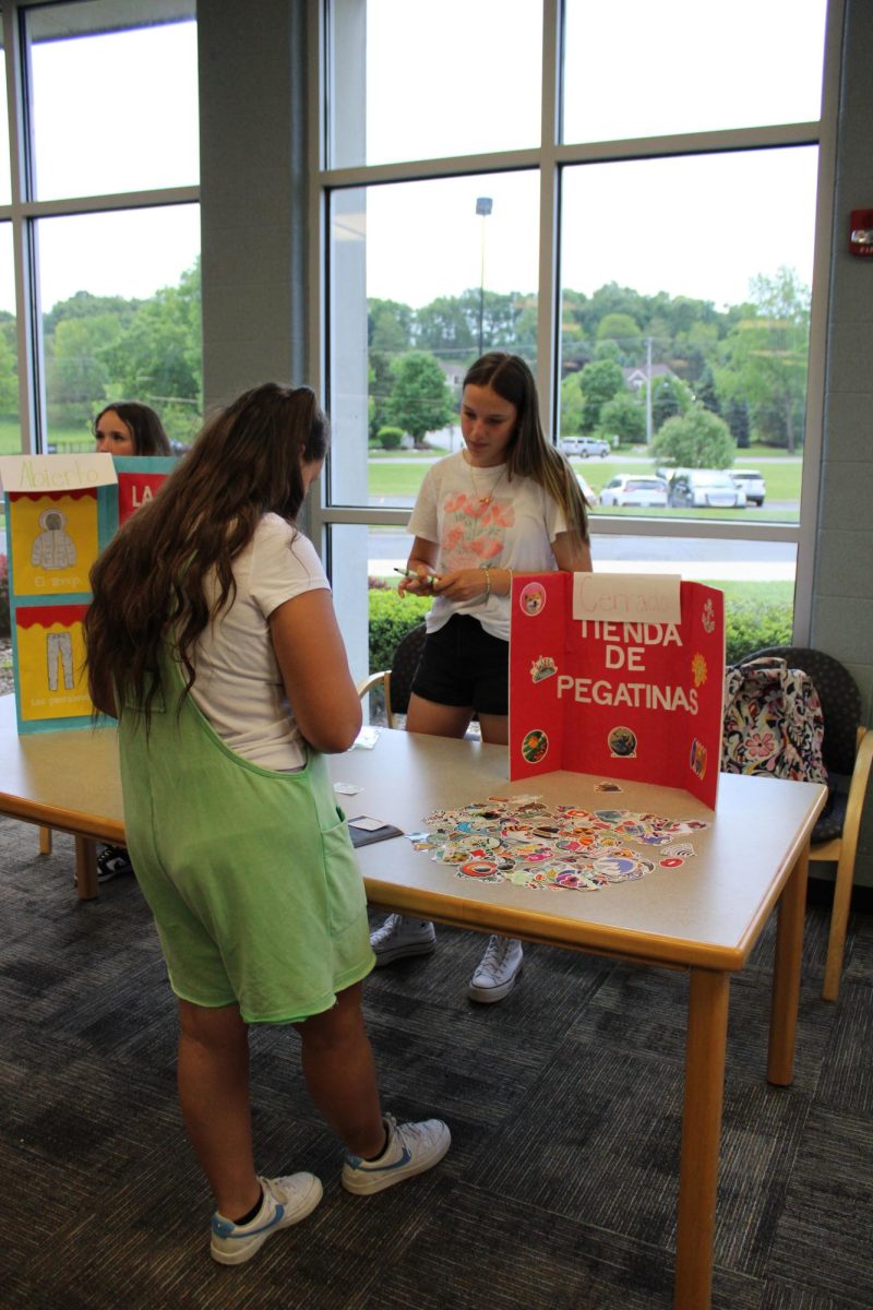 Bartering, sophomore Emily Kaplan sells stickers. On May 20, the Spanish 2 class took their end of the year exam.