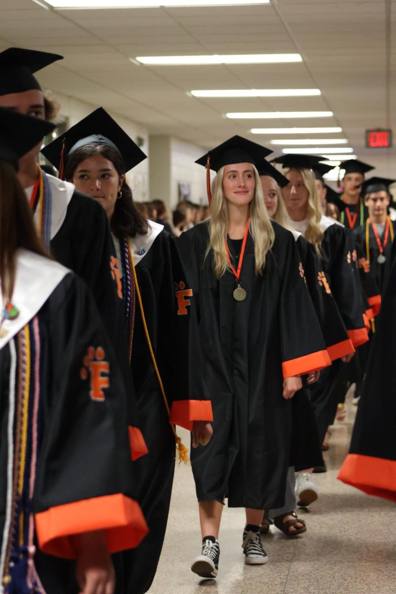 Smiling, senior Sophie Smith walks during the clap out. On May 22, the underclassmen lined the halls and clapped as the seniors walked out for their final time.