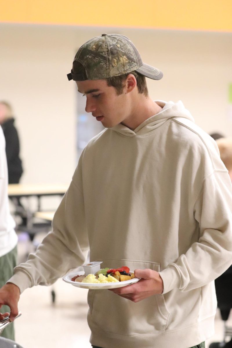 In line for breakfast, senior Cody Dawes grabs fruit. On May 21, there was a breakfast held for seniors before cap and gown pickup. 