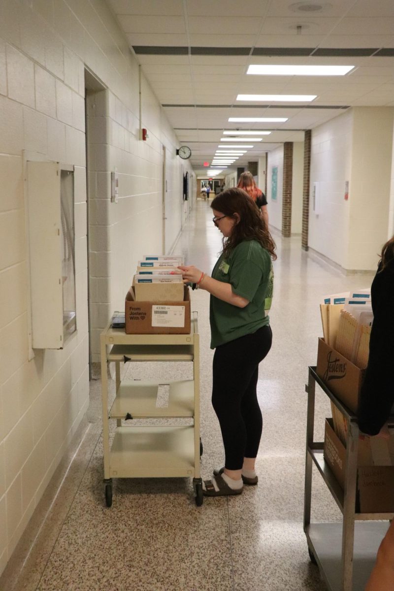 Grabbing a book, junior Hannah Jones distributes yearbooks to classes. On May, 21. yearbook staff passes out yearbooks. 