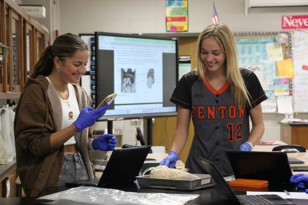 Smiling, senior Ella Pedlar and junior Alexandria Shouse work together in a lab. On May. 1, Anatomy students participated in a pig dissection.