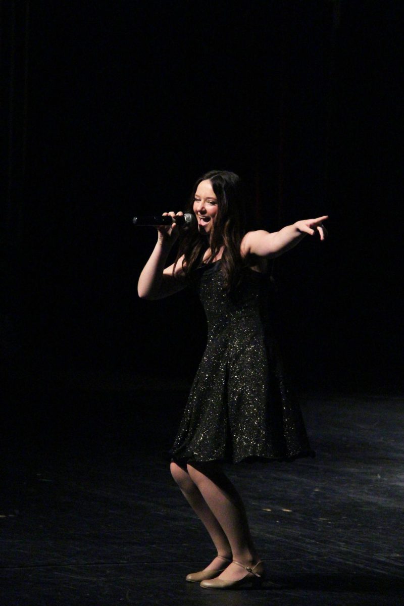 Singing, senior Emma Minock performs to the crowd. On May 10, the Ambassadors held their 45th annual show.