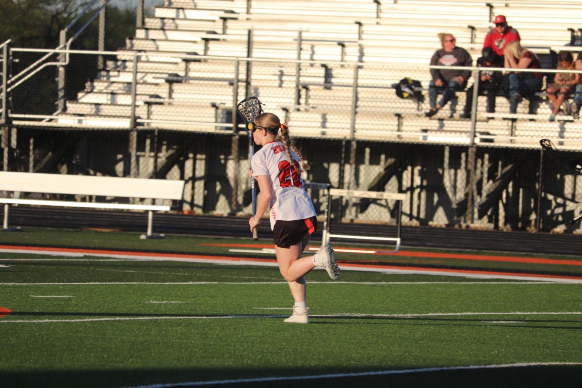 Holding the ball, sophomore Evie Metcalfe runs to make a goal. On May 6, the varsity lacrosse team played Swartz Creek and lost 3-15.