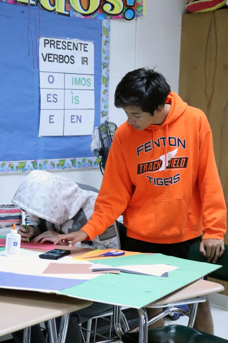 Looking down, sophomore Alexander Morello works on a poster. On May 13, Spanish 3 classes prepped for a market.