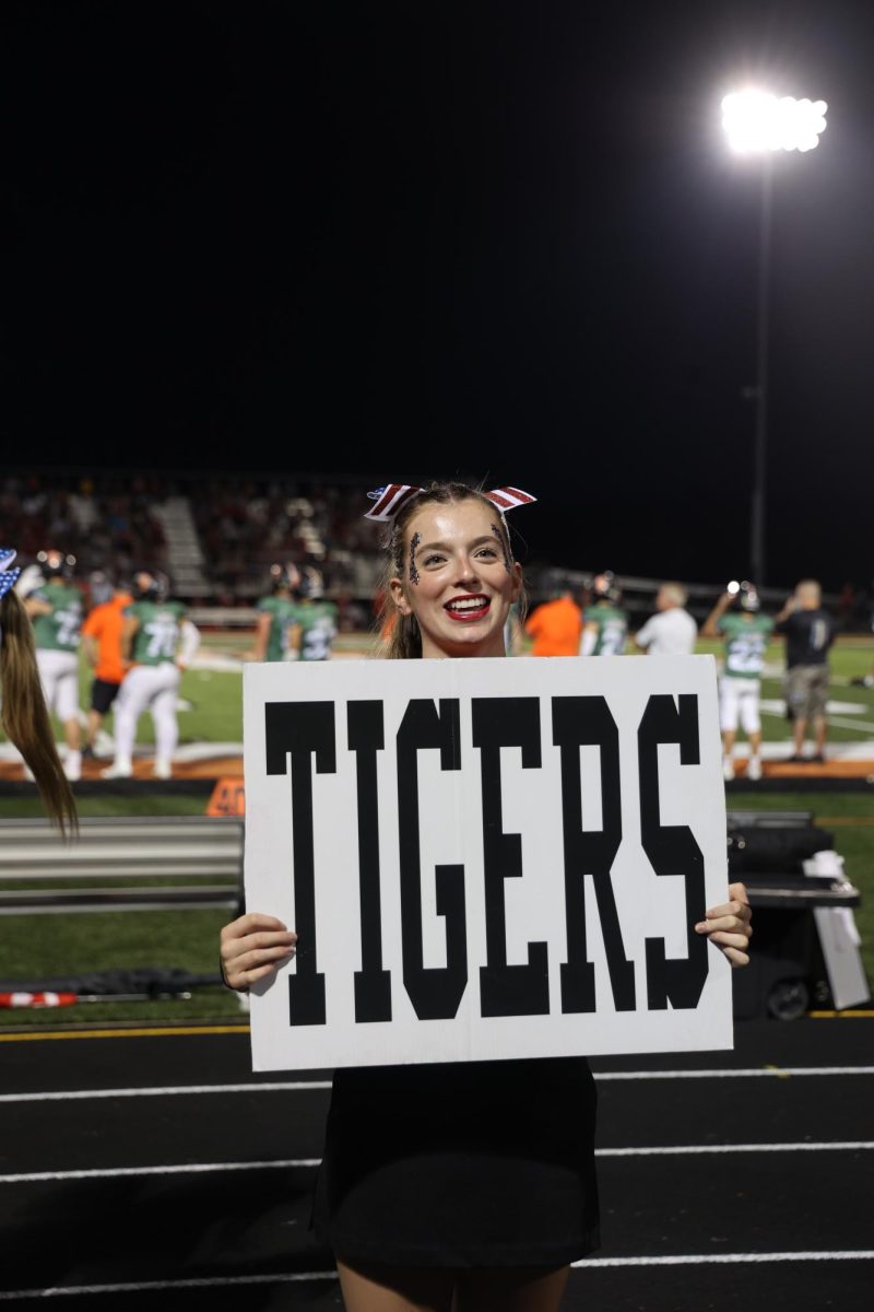 Smiling at the crowd, senior Sophia Markley cheers for the Tigers. On Sept. 20, Fenton beat Holly at Heros night.