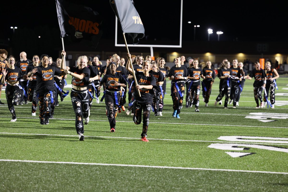 Smiling, seniors Izzy MacCaughan and Olivia Kowalski run the flags across the field. On Sept. 23, the seniors beat the juniors 27-12 in the powderpuff game.