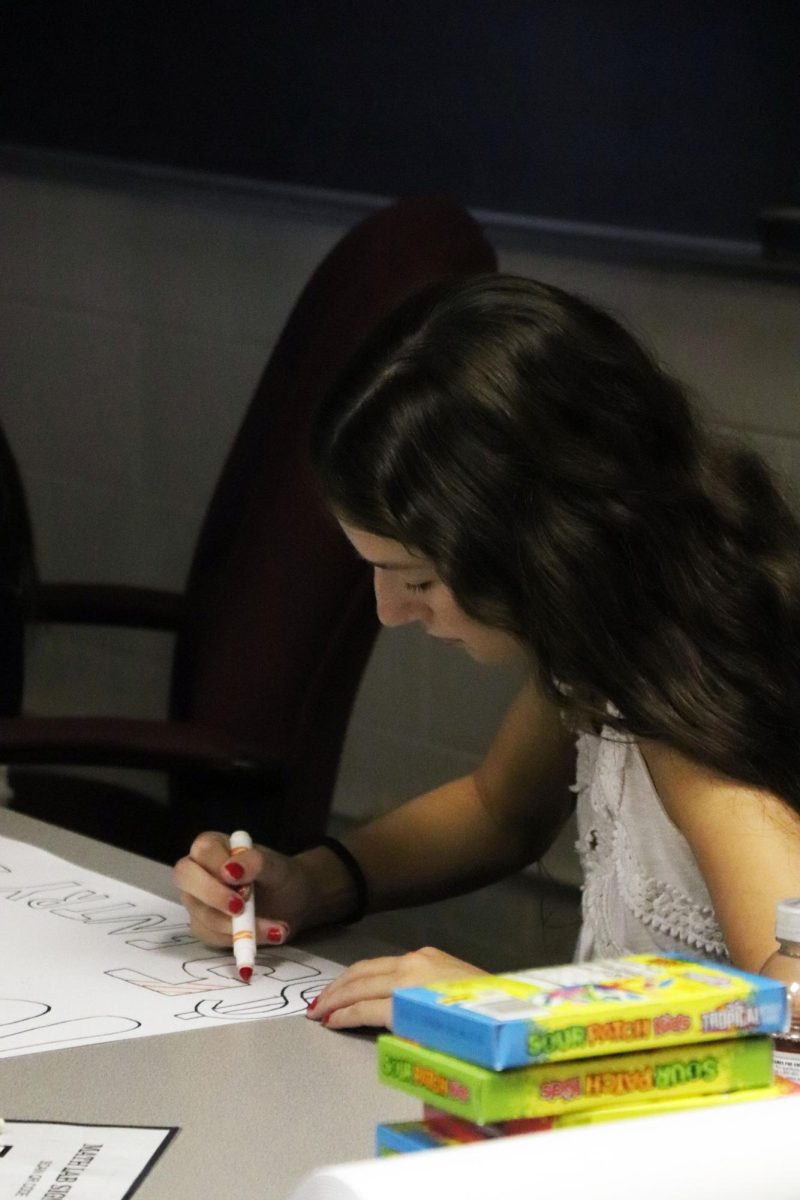 Coloring, junior Addison Smith makes a sign for powderpuff. On Sept. 12, Student Council met to continue planning for Homecoming. 