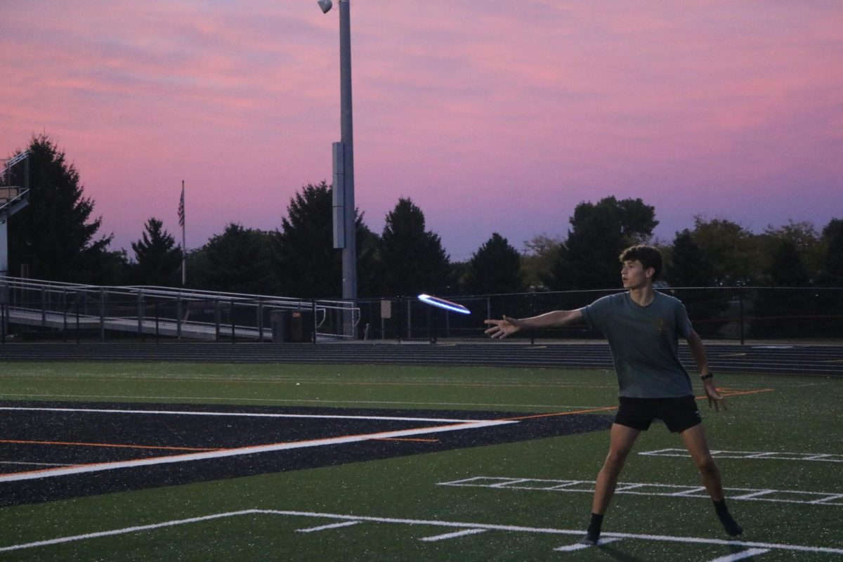 Throwing a frisbee, sophomore Jackson Defina plays with a frisbee. On Sept. 26, the cross country team spent the night on the field.