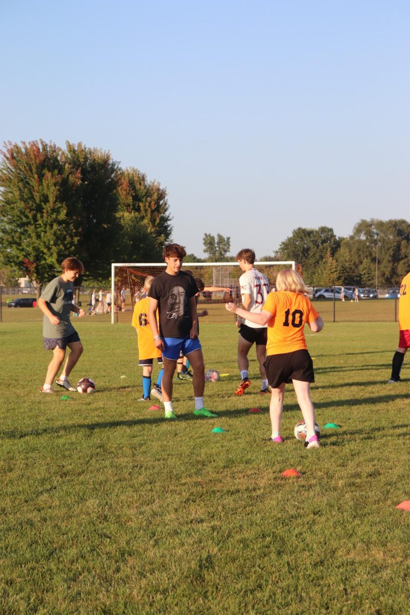 Guiding his viper, junior Dillon Hamilton helps Molly Katic shoot the ball through the cones. On Sept. 17, the boys soccer team held a practice with the Vipers soccer team.