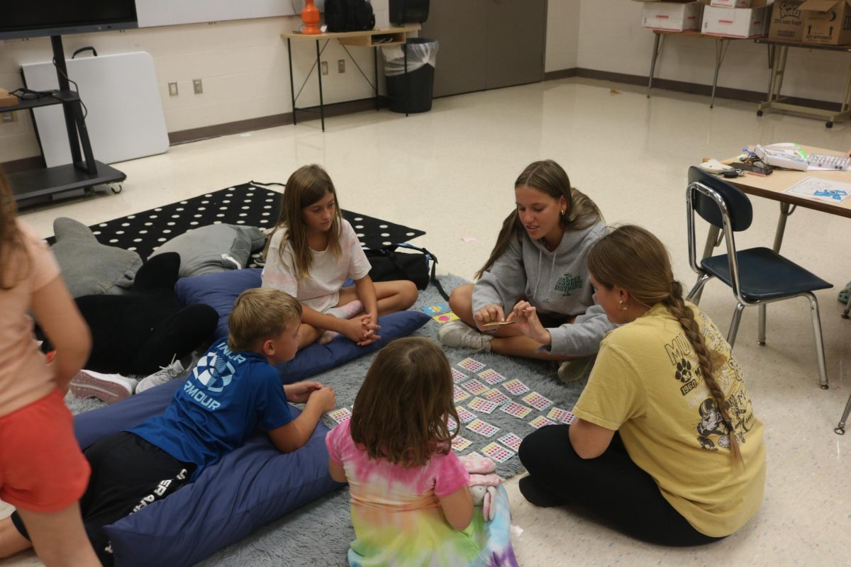 Passing out cards,  junior Emily Kaplan volunteers at Tomek Elementary school. On Sept. 10, Kaplan helped her peers look after the elementary students for NHS. 