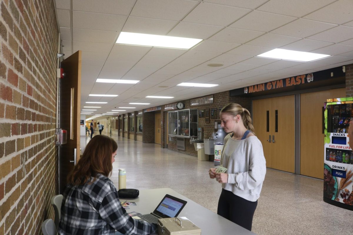 Purchasing her homecoming ticket, junior Evie Metcalfe prepares for the upcoming dance. On Sept. 28 Fenton hosted their annual school dance.