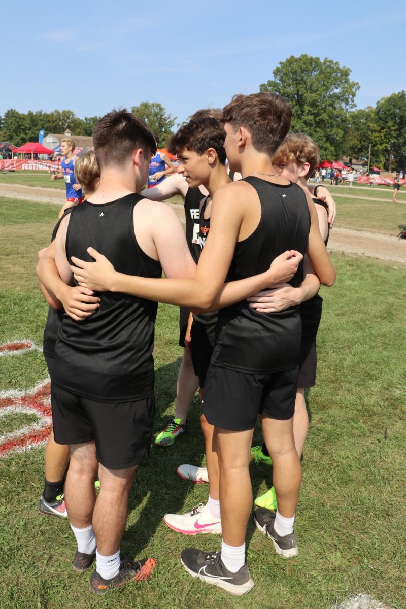 Hudling up, sophomore Jackson Defina leads the "Tiger prayer"along with his fellow teamates. On Sept. 14, the JV boys Cross Country team prepares for their race.