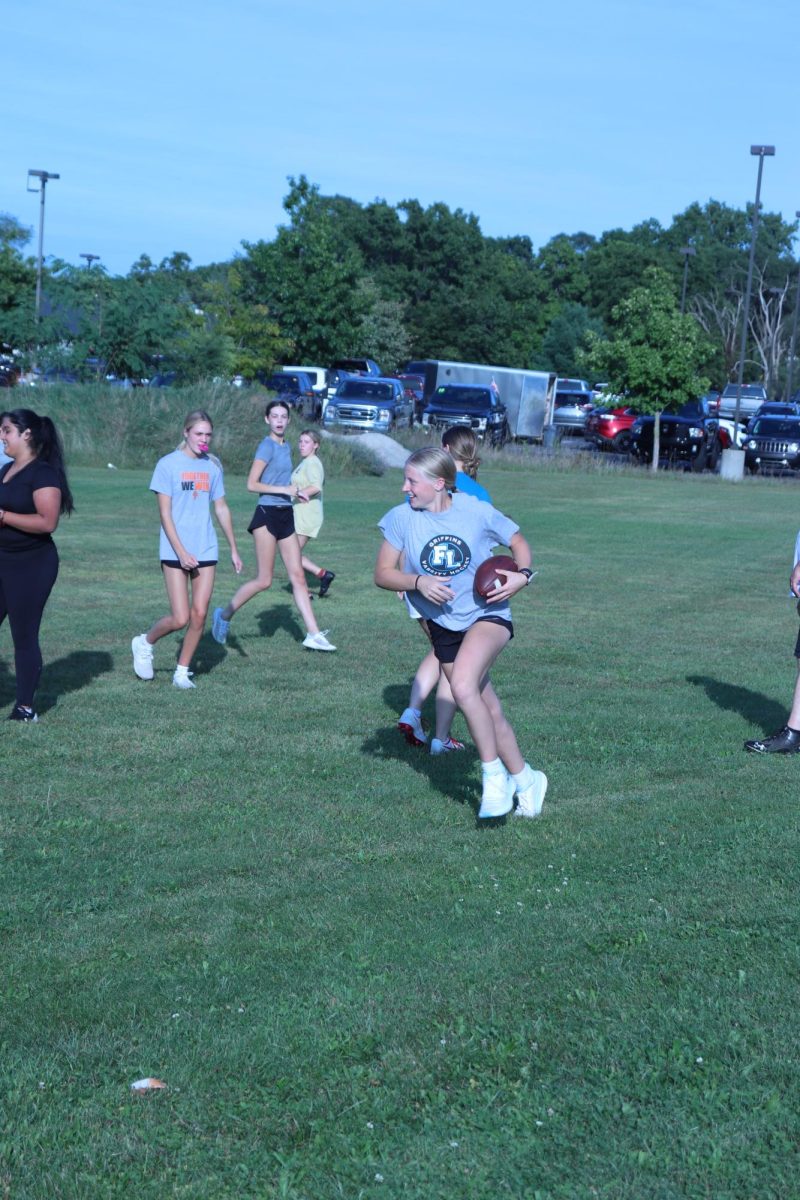 Training, senior Izzy MacCaughan is running with a football. On Sept. 10, MacCaughan practiced for the fenton powderpuff game against the fenton junior class. 