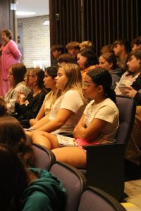 Sitting, freshman Isla Diener listens to Mr. Bakker give a speech at the freshmen class meeting. On Sept. 5th, students gather into the Ruby Zima Auditorium.