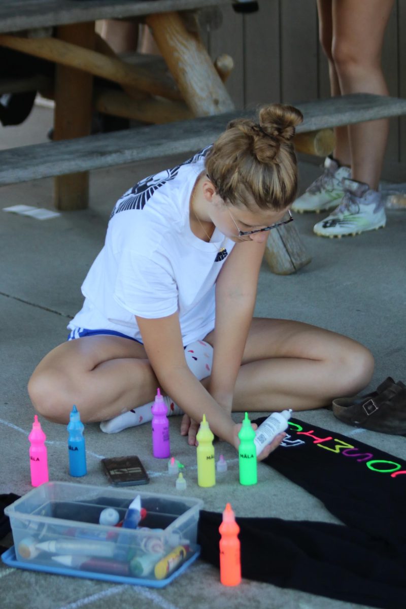 Painting with colorful puffy paint, senior Addi Browne gets her pants ready for powderpuff day. On Sept. 21 the senior girls who are participating in powderpuff painted their pants to show off their school spirit. 