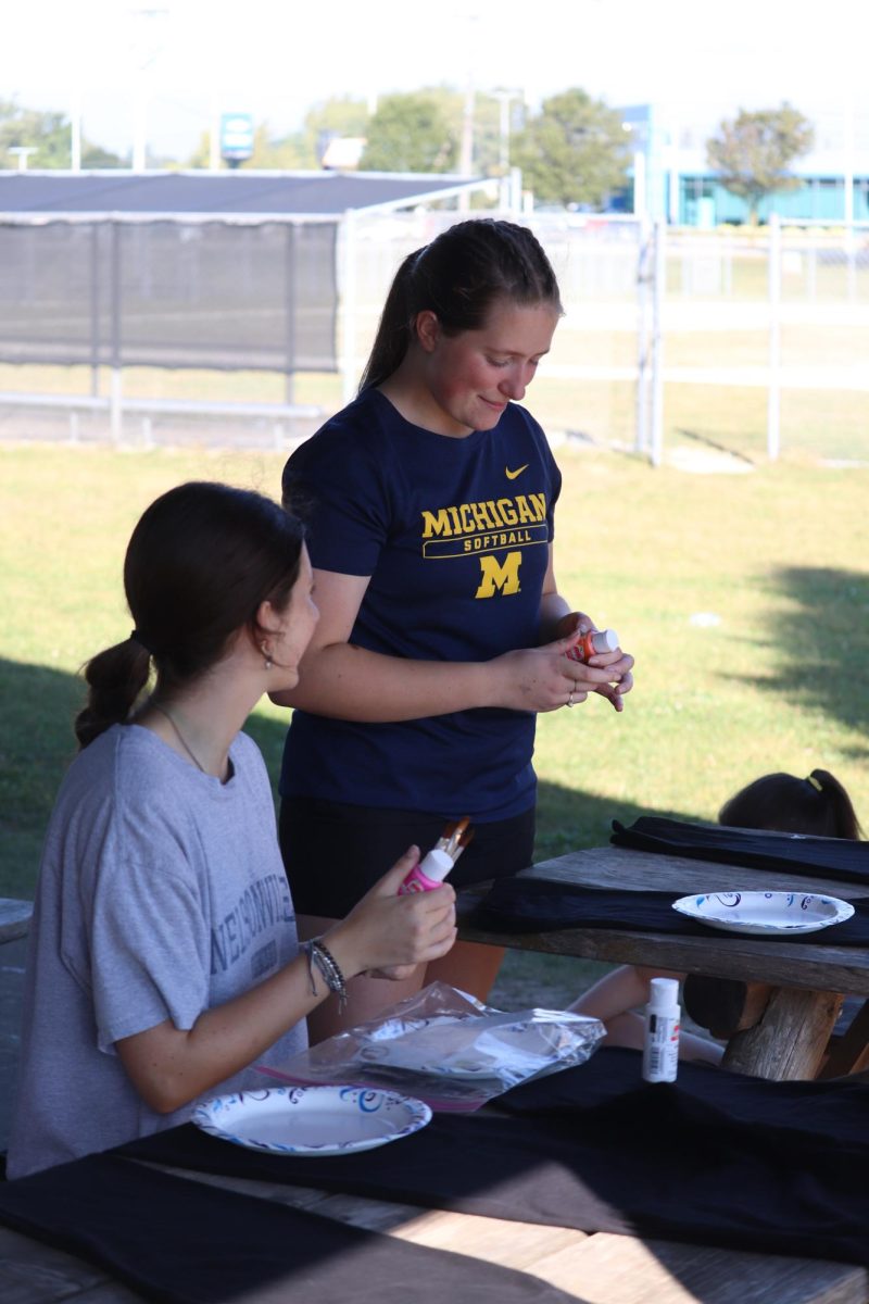 Opening the paint, senior Zoe Plunkett starts to made her powder puff pants. On Sept. 21, the senior girls decorated sweatpants for the powder puff game. 