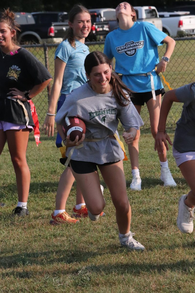 Carrying the football, senior Paige Harrison attempts to run around the defender. On Sept. 12, the seniors held their 4th powder puff practice.